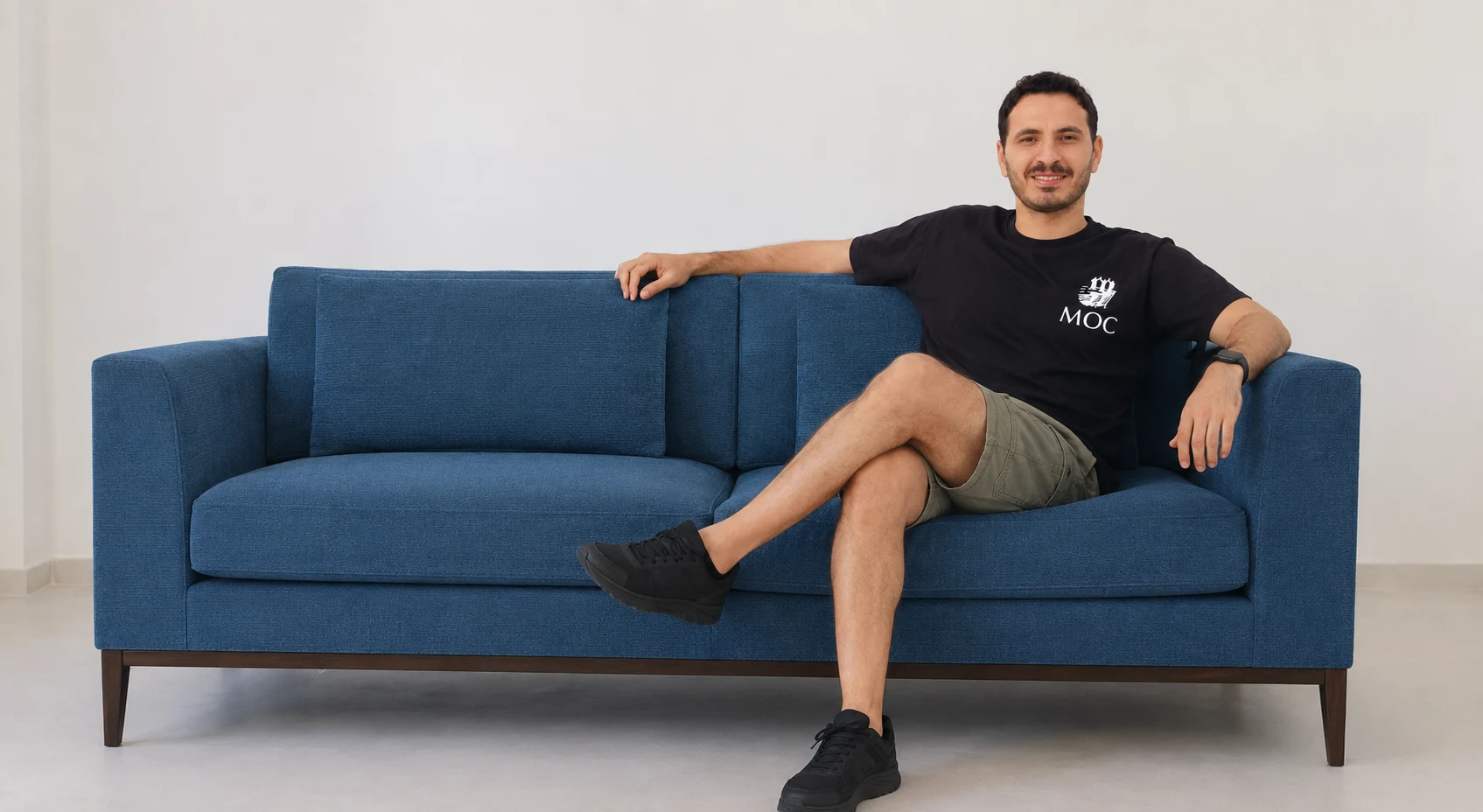 A man relaxing on a deep blue Grees& sofa