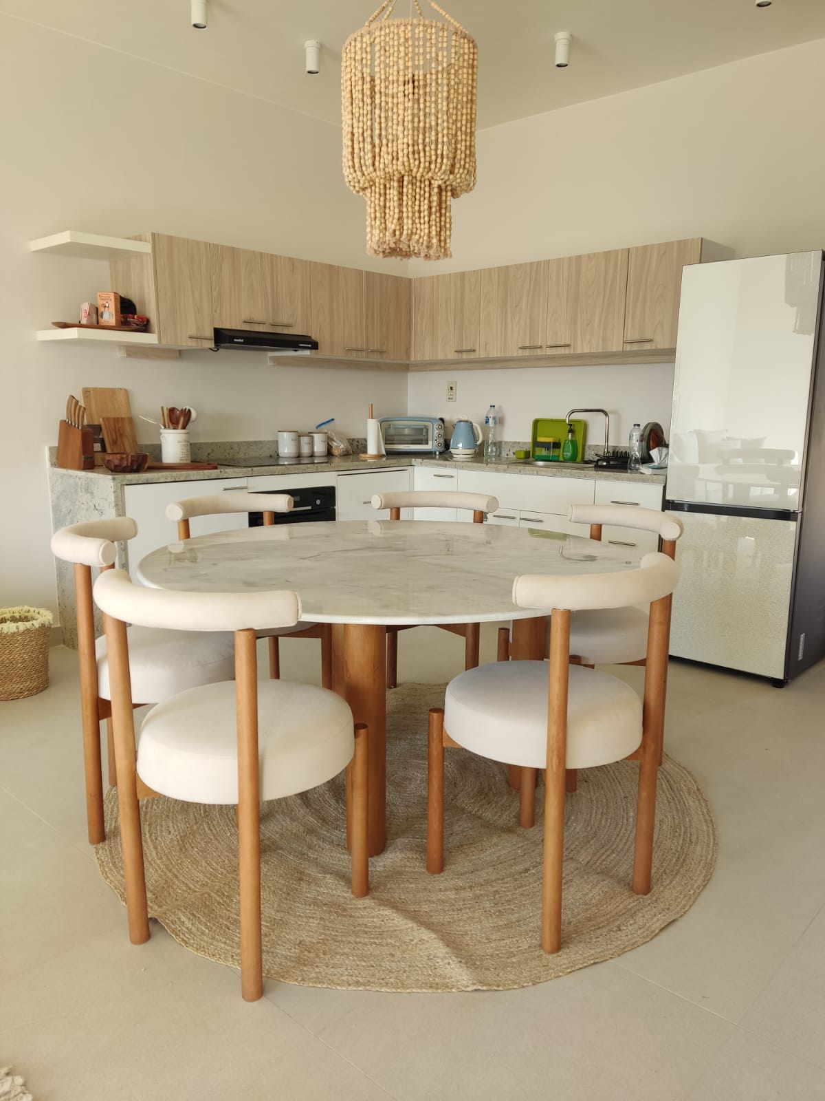 A round marble-top dining table with cream upholstered chairs in a client's home in Sheikh Zayed