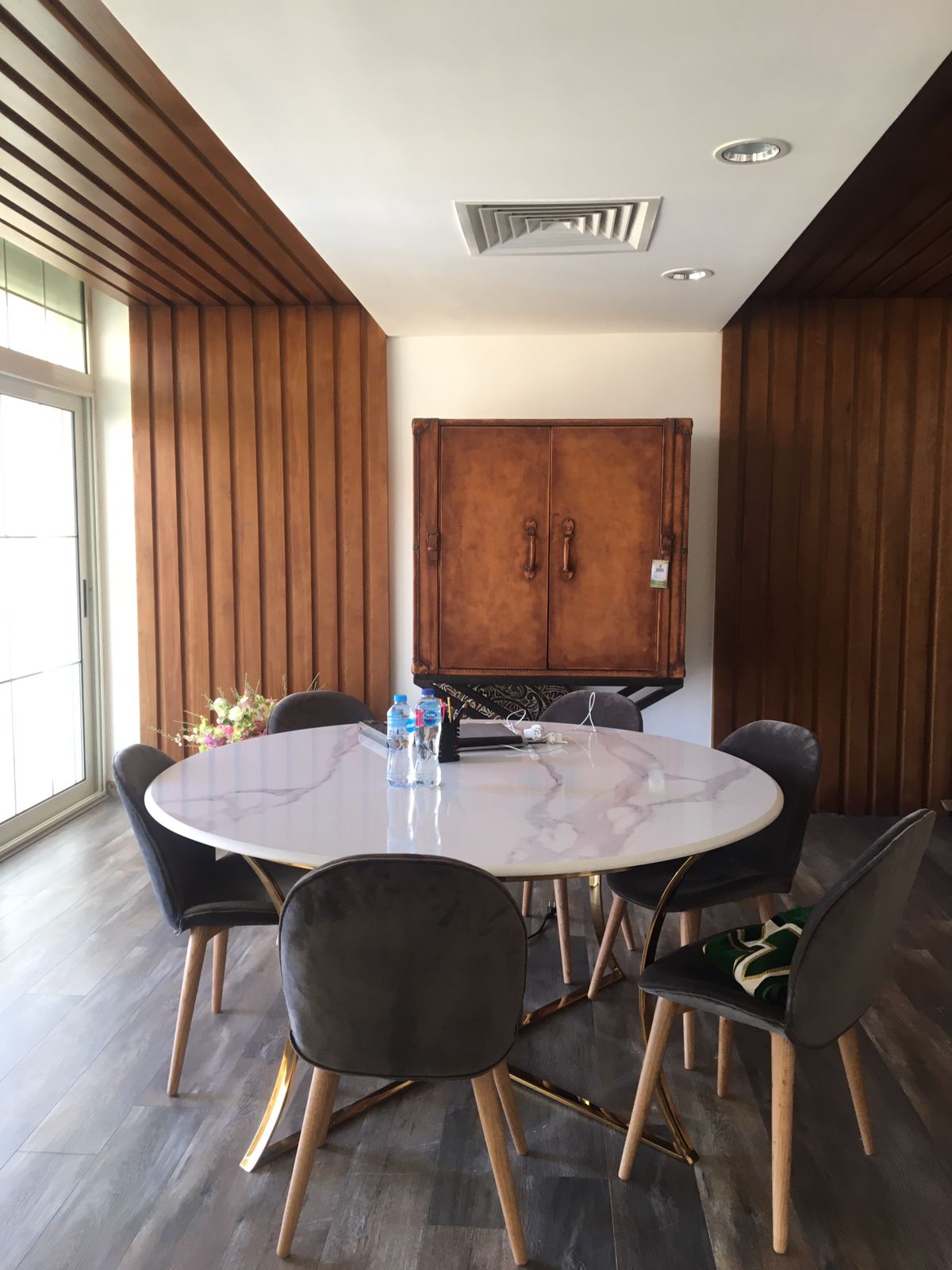A round marble dining table with grey velvet chairs delivered in Sheikh Zayed
