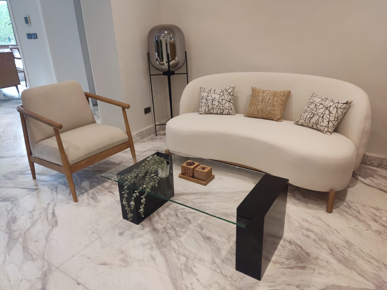 A curved cream sofa with a glass coffee table on marble floors, delivered to a Sahel home